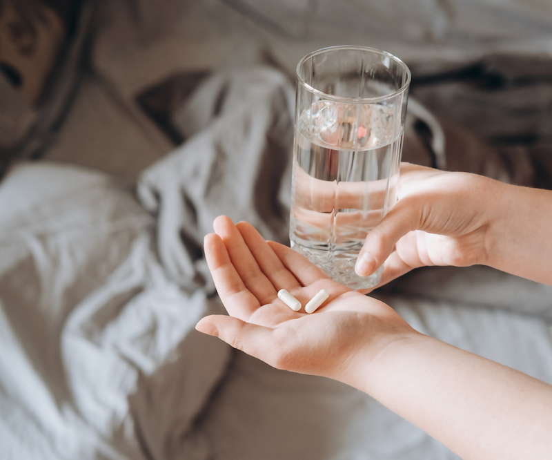 hands-of-young-woman-holding-pills-and-glass-of-wa-2022-01-11-21-27-56-utc